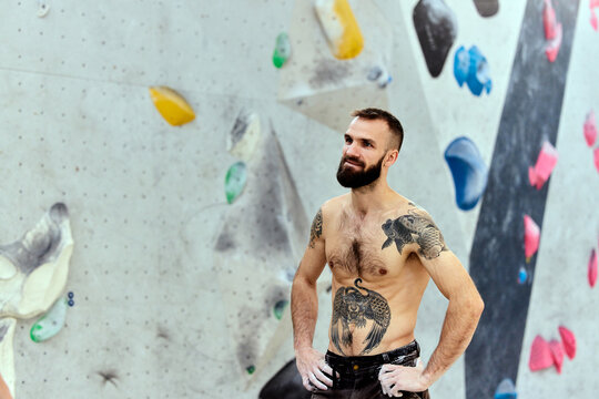 Fit man with tattoos standing in a climbing gym