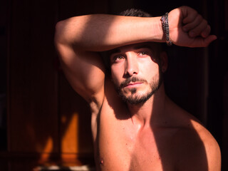 Portrait of sexy shirtless muscular man next to window