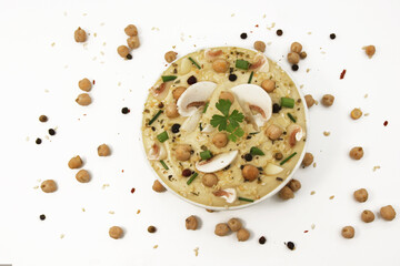 Top view of hummus with mushrooms on a white background in a plate topped with chickpeas and sesame seeds, onion, parsley and spices. Culinary and food menu photo. Eastern or Mediterranean cuisine