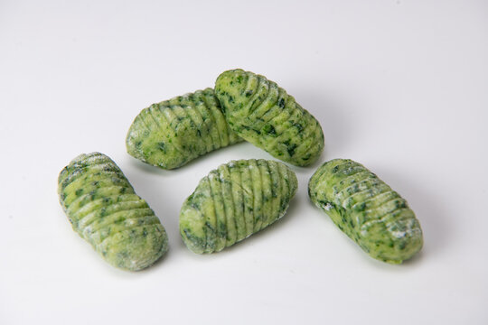 Pile of green spinach gnocchi dough dumplings isolated over the white background, High quality photo