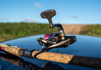 Fishing rod, spinning reel on the hood of the car