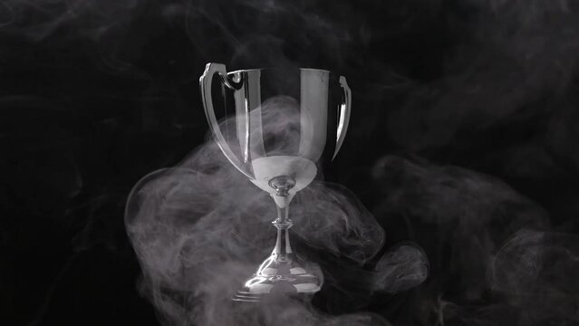 Silver Trophy turn around competition in the dark on the black background with smoke, Spectacular success Concept	