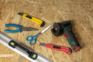 A worker holds a grinder on the background of a work table with tools at a construction site. construction concept.