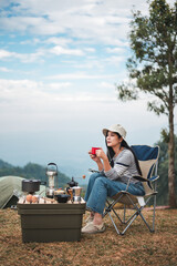 Hipster asian woman camper relaxing and enjoying camping alone ,drinking coffee in the morning
