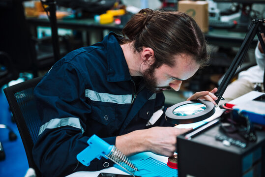 Caucasian man specialist robotic engineers maintenance on .circuit board robotic controller in repair department, Testing new program on automatic robot machine.