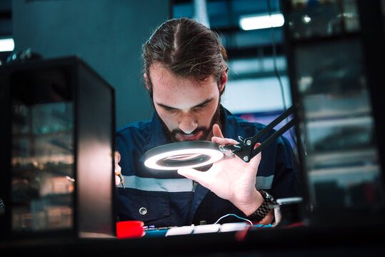 Caucasian man specialist robotic engineers maintenance on .circuit board robotic controller in repair department, Testing new program on automatic robot machine.