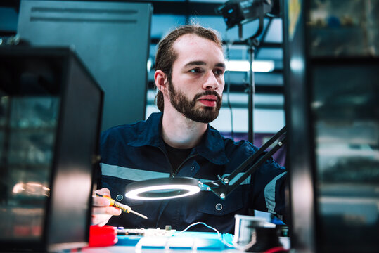 Caucasian man specialist robotic engineers maintenance on .circuit board robotic controller in repair department, Testing new program on automatic robot machine.