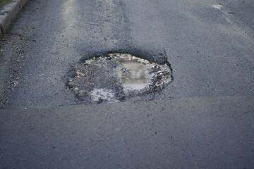 hole in the asphalt, a puddle with muddy water, a destroyed road, the reflection of a house in a puddle, a hole on the road filled with water, a destroyed road, a road surface covered with a pit
