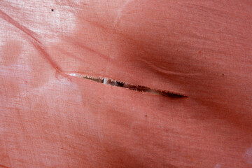 Extreme close-up of a child's eyes peeking through torn red cloth.