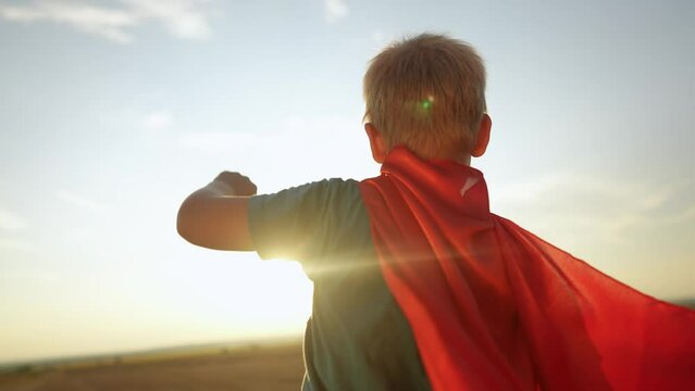 kid superhero. boy happy family a dream concept. baby boy superhero close-up in red cape at sunset. portrait child superhero close-up from the back. strength lifestyle fantasy concept