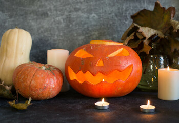 A carving pumpkin with candles and pumpkins on gray background.