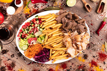 Doner Kebab Bowl with Mixed Meat, Fries, and Fresh Vegetables.
Colorful doner bowl featuring a mix of sliced chicken and beef, served with French fries, lettuce, tomatoes, cucumbers, and red peppers. 
