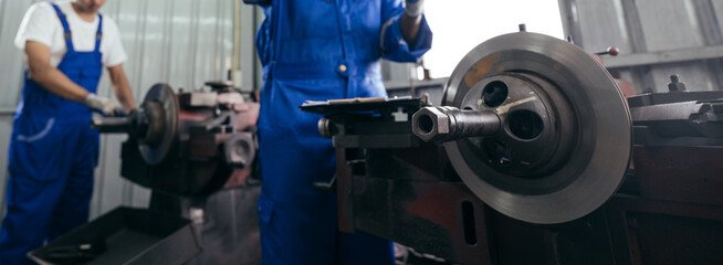 Naklejka na ściany i meble Background of mechanic worker or metalworker using metal lathe machine operate polishing car disc brake at auto repair garage. Maintenance automotive and inspecting vehicle part concept