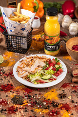 Doner Kebab Bowl with Chicken, Fries, and Fresh Vegetables.
Takeaway bowl filled with sliced grilled chicken doner, French fries, cucumber, tomato, lettuce, and red pepper. Styled on a rustic wooden t