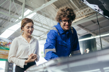 Fototapeta na wymiar Caucasian repairman or car mechanic showing and explaining vehicle broken part and maintenance report to customer at auto repair shop. After service concept