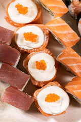 Assorted Sushi Platter with Salmon, Tuna, and Avocado Rolls on Turquoise Background. Vibrant sushi platter featuring a variety of maki and nigiri rolls with salmon, tuna, avocado, and cream cheese. Se