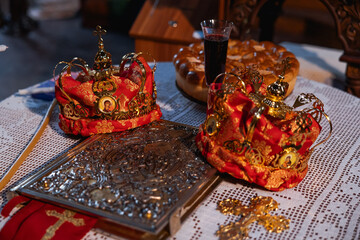 Crowns for weddings in orthodox church. Attributes - gold crowns, golden cross, bible, candles, church altar.