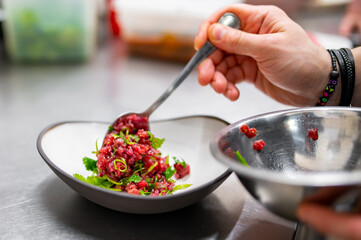 professional chef's hands cooking Raw beef meat tartar in restaurant kitchen