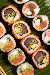 Assorted Sushi Platter with Salmon, Tuna, and Avocado Rolls on Turquoise Background. Vibrant sushi platter featuring a variety of maki and nigiri rolls with salmon, tuna, avocado, and cream cheese. Se