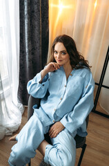 Portrait of a beautiful woman in a light blue suit, who is sitting in a chair.