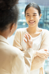 Asian woman talking fluently with her African friend, concept image of good command in foreign...