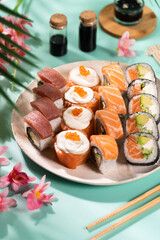Assorted Sushi Platter with Salmon, Tuna, and Avocado Rolls on Turquoise Background. Vibrant sushi platter featuring a variety of maki and nigiri rolls with salmon, tuna, avocado, and cream cheese. Se