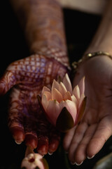 Mehndi adorns the women's hands with a beautiful flower design.Vesak day, Buddhist lent day, Buddha's birthday worshiping concept with woman's hands holding water lilly or lotus flower 