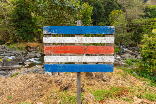 Costa Rica, Symbol of the country, Colors of the National Flag painted on a wooden palette against the background of the jungle