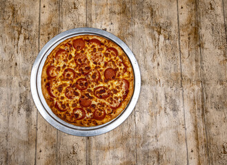 Pepperoni Pizza on wood background and silver plate