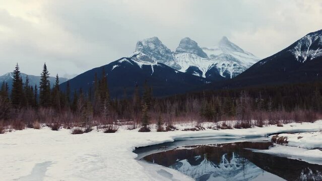 Three Sisters Mountains with snow covered on bow river reflection in the morning on winter at Canmore