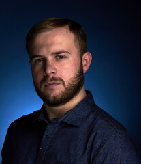 Obraz premium Portrait of a young confident blonde in a dark shirt, with a beard on a dark background