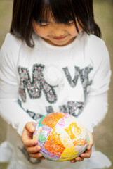 Young asian girl holding colorful paper mache egg in her hand in Easter