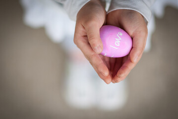 Young asian girl holding colorful Easter egg in her palm of her hand