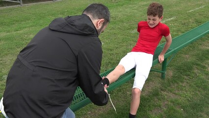 Handheld shot of an injured youth football player and his coach on the sidelines