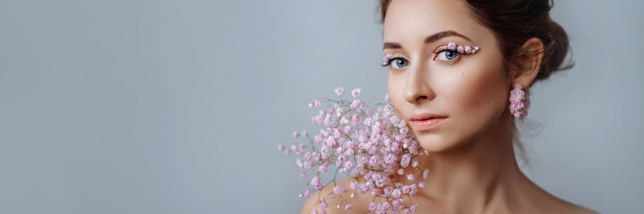 Portrait of a beautiful brunette woman with perfect skin and creative floral makeup look. The...