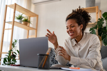 Young African ethnicity businesswoman working from home sitting in front of a laptop computer having a meeting over the internet. Woman freelance entrepreneur. 