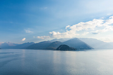 Beautiful aerial view of the famous Como Lake on sunny summer day. Clouds reflecting in calm waters of the lake with Alp mountains on the background.