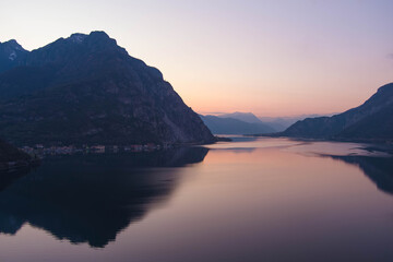 Beautiful aerial view of the famous Como Lake on purple sunset. Mountains reflecting in calm waters of the lake with Alp mountain range on the background.