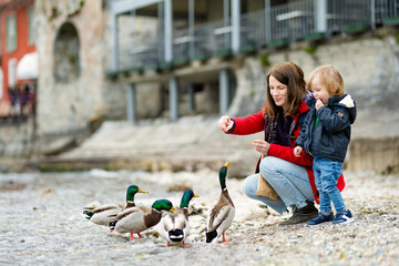 Mother and her toddler son feeding ducks in Varenna, one of the most picturesque towns on the shore...
