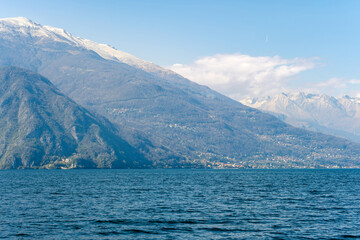 Beautiful aerial view of the famous Como Lake on sunny summer day. Clouds reflecting in calm waters of the lake with Alp mountains on the background.