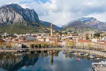 Fototapeta na wymiar Sunny aerial cityscape of Lecco town on spring day. Picturesque waterfront of Lecco town located between famous Lake Como and scenic Bergamo Alps mountains.