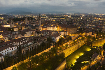 Obraz premium Scenic aerial view of Bergamo city northeast of Milan, on cloudy evening. Flying over Citta Alta, town's upper district encircled by Venetian walls. Bergamo, Italy.