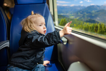 Toddler boy traveling by train. Little child sitting by the window in express train on family...