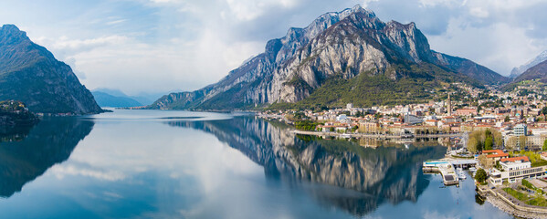Sunny aerial cityscape of Lecco town on spring day. Picturesque waterfront of Lecco town located between famous Lake Como and scenic Bergamo Alps mountains. - obrazy, fototapety, plakaty