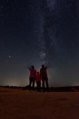 Naklejka na ściany i meble Parents with their daughter watching the milky way