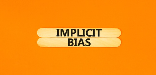 Implicit bias symbol. Concept words Implicit bias on wooden sticks. Beautiful orange table orange background. Business psychology implicit bias concept. Copy space.
