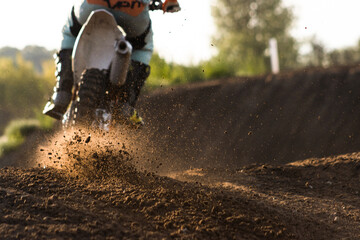 A young man, a man, an athlete, driving a motocross motorcycle in the blur, on a dirt track. Movement, blur, slow-motion, field. Evening, sunset.