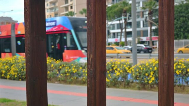 blurred tram and city traffic seen from behind wooden railing