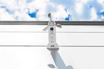 White wind speed sensor, on the wall building sky background. Vane anemometer.