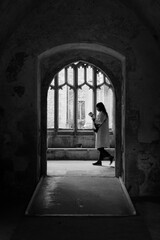 Silhouette of a woman reading while walking in a historic building